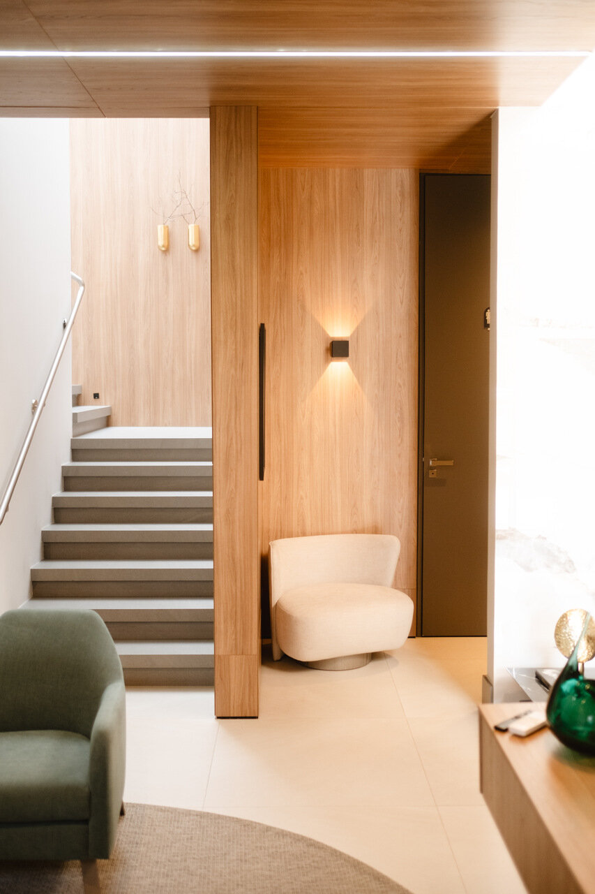 Hall com escada, poltrona bege e revestimento em madeira